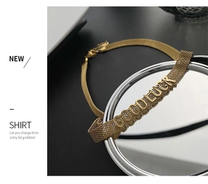 Détail d'un collier en maille dorée avec lettrage GOODLUCK sur un miroir rond