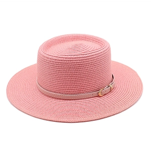 Dettaglio del cappello di paglia rosa a tesa larga con fibbia decorativa in metallo