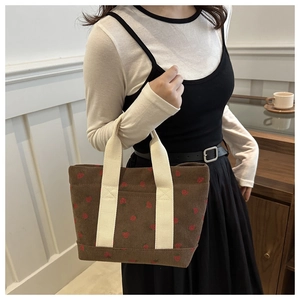 Close-up of brown corduroy strawberry bag texture with sturdy off-white strap