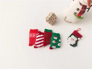 Flat lay of four Christmas cotton socks featuring Santa Claus, snowflakes and green stripes