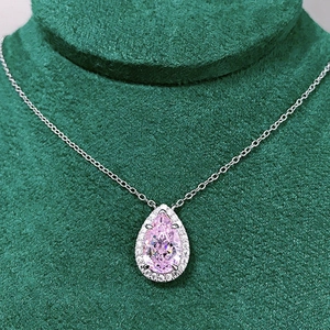 Macro detail of pear-shaped pink gemstone necklace with white diamond halo setting