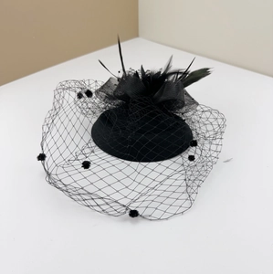 Detail view of black vintage fascinator with polka dot mesh veil and feather accents