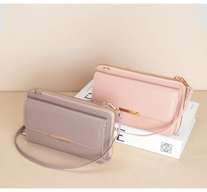 Close-up of slim long wallets in pastel pink and purple with gold hardware and shoulder straps