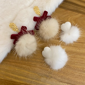 Close-up of heart-shaped plush earrings with red velvet bow and golden metal texture