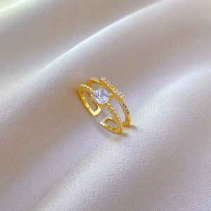 Macro shot of gold bow ring with square crystal on champagne silk background
