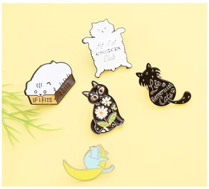 Set of five colorful cat enamel pins with various slogans on a light yellow background