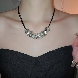 Detail showing twisted silver metal rings on a black leather cord necklace worn by model