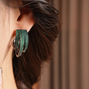 Close-up of sparkling green zircon multi-layer C-shaped earrings on model ear