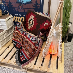 Bohemian geometric woven camping blanket with tassels displayed in an outdoor setting