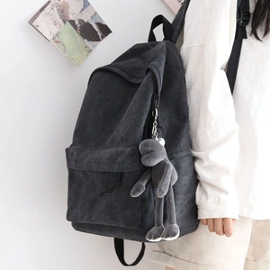 Side view of a large grey canvas backpack with a cute long-legged frog plush keychain