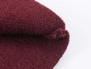 Vue macro montrant la texture en tricot bordeaux dense et la qualité du fil du vêtement