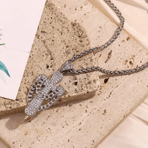 Detailed view of silver cross pendant with rhinestones on a natural stone surface