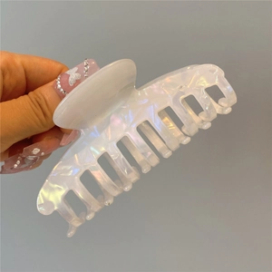 Macro detail of white pearlescent acetate hair claw clip showing glossy shark fin design