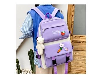 Detail of purple and beige canvas backpack with cute plush bear and strawberry pins