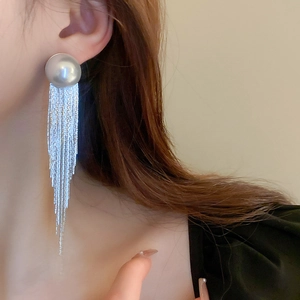Close-up of long silver fringe earrings with large round pearls on a model's ear