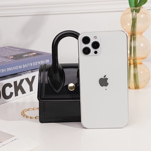Black glossy jelly mini handbag with gold chain strap next to a phone for size reference