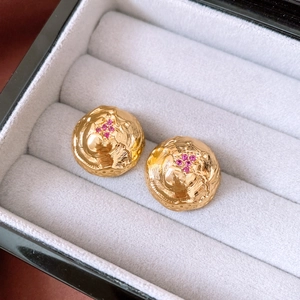 Macro detail of vintage 18k gold plated round earrings with pink gemstone inlay