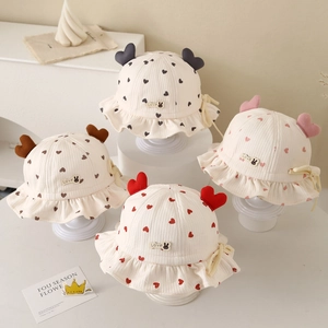 Detailed view of four infant sun hats with heart prints and adjustable straps on pedestals