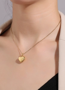 Polished gold heart pendant necklace shown on a model with a minimalist chic style