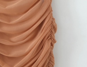Gros plan sur les détails froncés en maille d'une élégante robe plissée couleur abricot