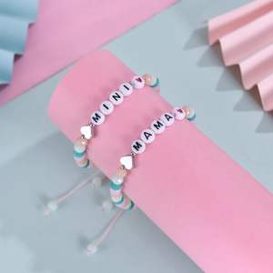 Detail of colorful beaded bracelets with MINI and MAMA letter charms on pink cord