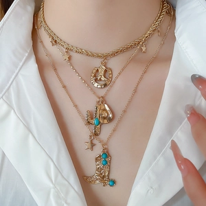 Macro view of gold-toned layered necklace with cowboy boot, star, and cactus charms