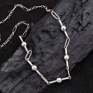 Minimalist silver bead link necklace featuring sleek rectangular chains on a textured background