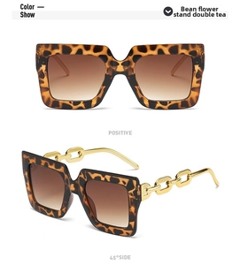 Detalle de gafas de sol de leopardo oversize con patillas de cadena dorada y lentes marrones