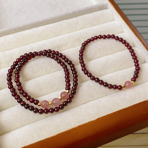 Close-up of garnet and strawberry quartz beaded bracelets set with gold metal accents