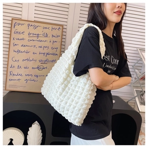 Detailed view of white pleated cloud bag texture shown in a bright lifestyle setting