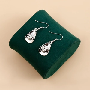 Détail de boucles d'oreilles chapeau de cowboy en argent sur support en velours vert