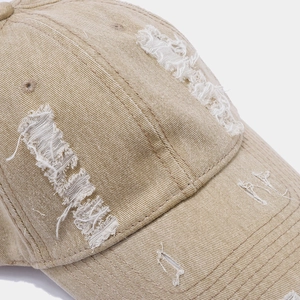Gros plan détaillé d'une casquette kaki délavée avec déchirures et bords effilochés