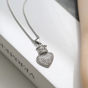 Macro shot of silver heart crown necklace with pavé cubic zirconia on a white book