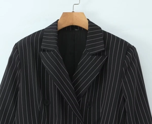 Détail du revers à pointe et des rayures verticales blanches sur le blazer noir chic