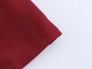 Detail of the dark red tweed fabric texture and precise stitching of the mini dress
