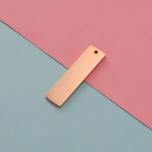 Close-up of a polished rose gold rectangular stainless steel pendant with a hanging hole