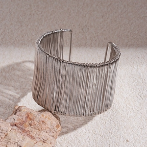 Detailed view of silver multi-layer wire-wrapped wide open cuff on natural sandstone background