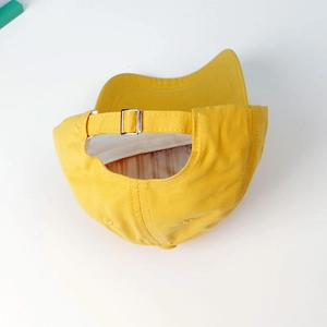 Detail of adjustable metal buckle and yellow cotton twill texture on children's baseball cap