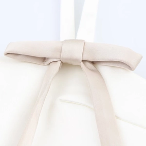 Close-up of champagne satin dress featuring a delicate silk bow-tie texture detail