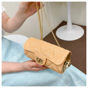 Detail of beige quilted patent leather cylinder bag with gold chain and pearl pendant