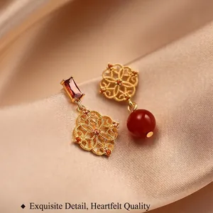 Elegant asymmetrical 18K gold-plated flower earrings with ruby stones on champagne silk