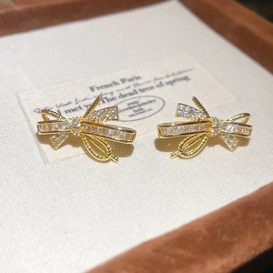 Macro shot of gold plated bow stud earrings with sparkling zircon inlay in a gift box