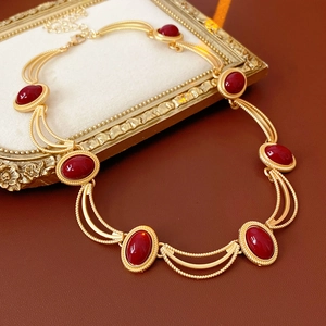 Detail of vintage gold necklace with oval red gemstones on a retro tray and leather background