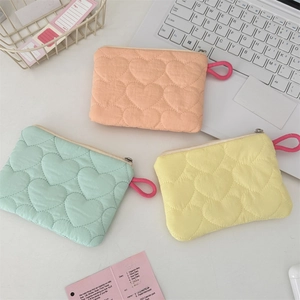 Close-up of heart-quilted fabric storage pouches in pink, mint green and soft yellow colors