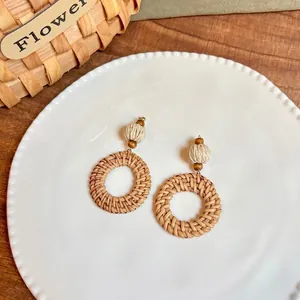 Close-up of handmade raffia teardrop earrings with woven texture and wooden beads