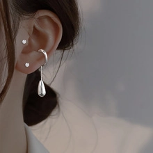 Close-up of a silver cat-paw ear cuff with water drop pendant worn on a female ear