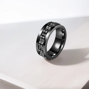 Detail view of a black titanium steel anti-anxiety ring with rotating gear texture.