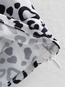 Detailweergave van een onzichtbare rits op een mouwloze top met zwart-witte luipaardprint