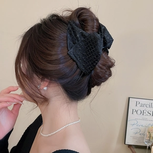 Close-up of a black acrylic bow hair claw with sparkling rhinestones on model's hair