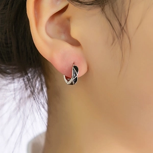Gros plan de boucles d'oreilles géométriques argentées avec émail noir portées